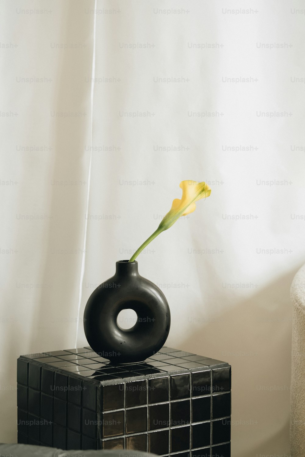a black vase with a yellow flower sticking out of it