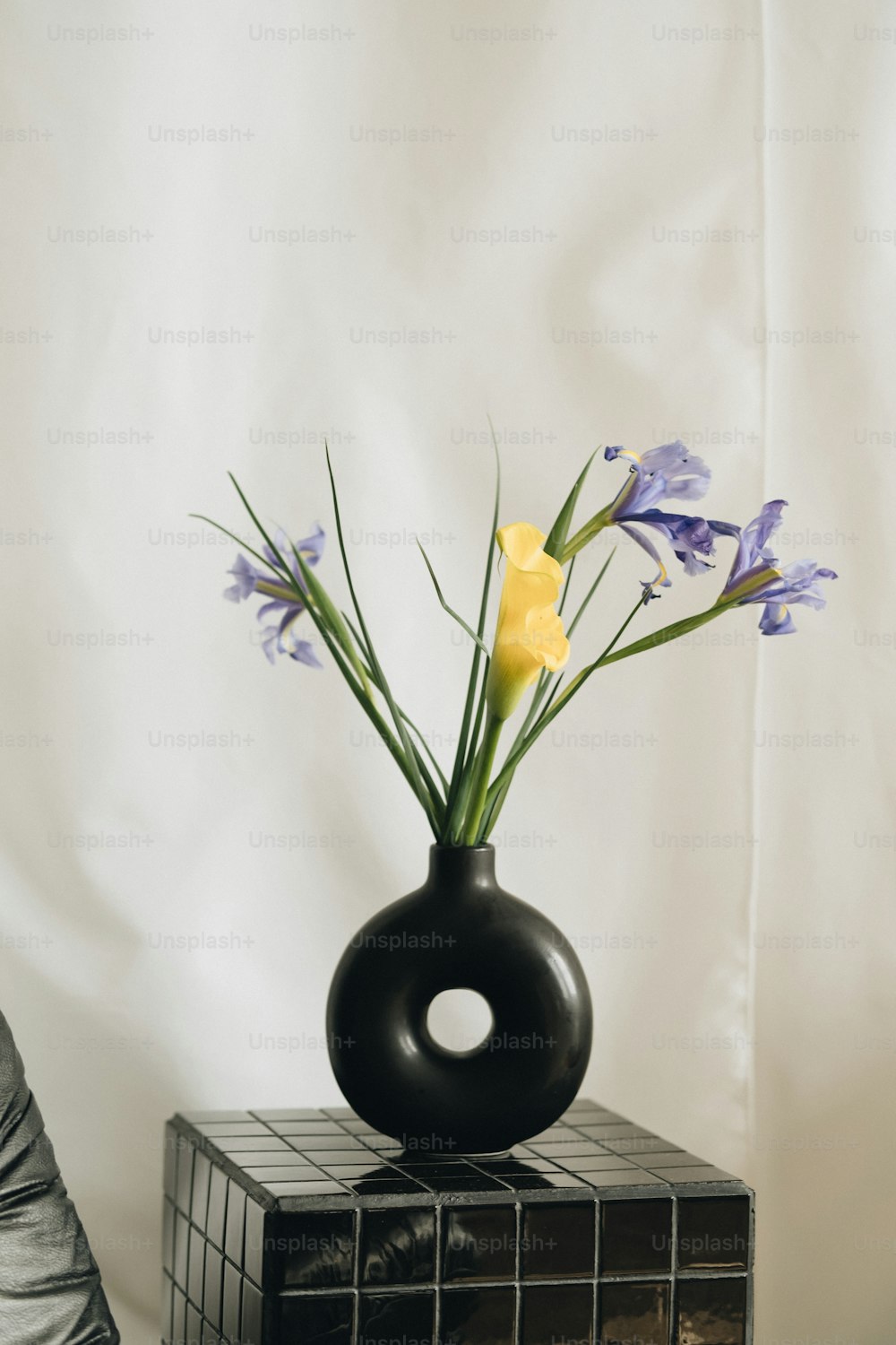 a black vase with yellow and purple flowers in it