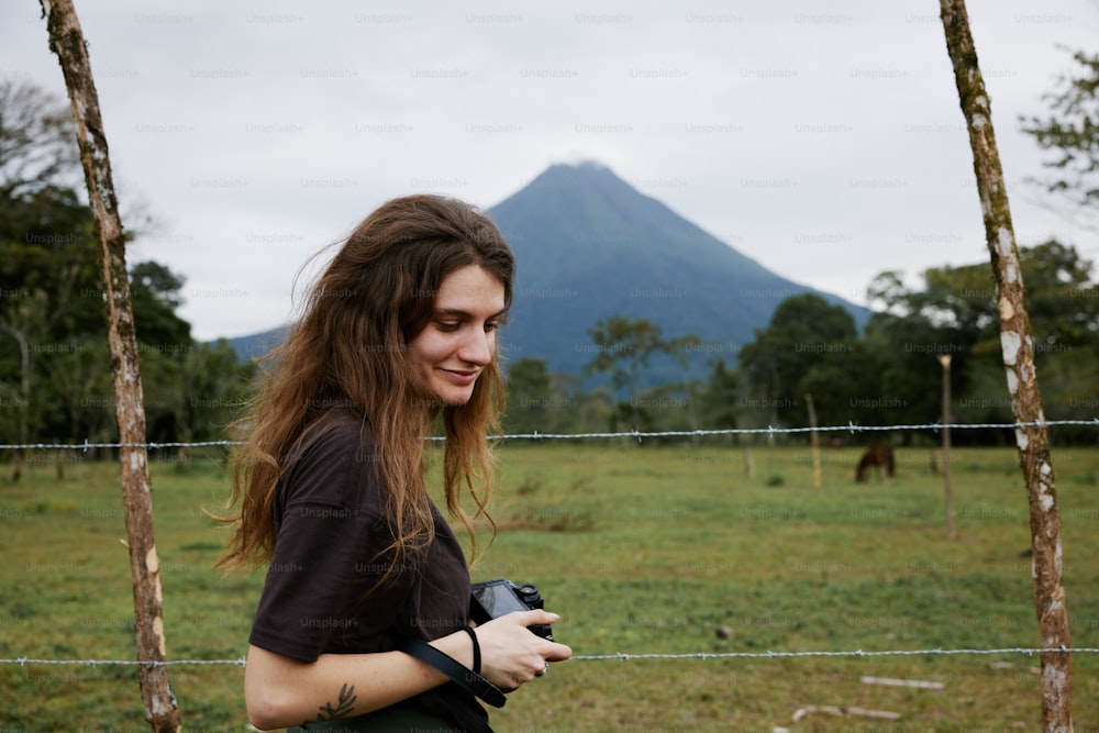 uma mulher segurando uma câmera na frente de uma cerca