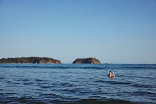 uma pessoa nadando no oceano perto de uma pequena ilha
