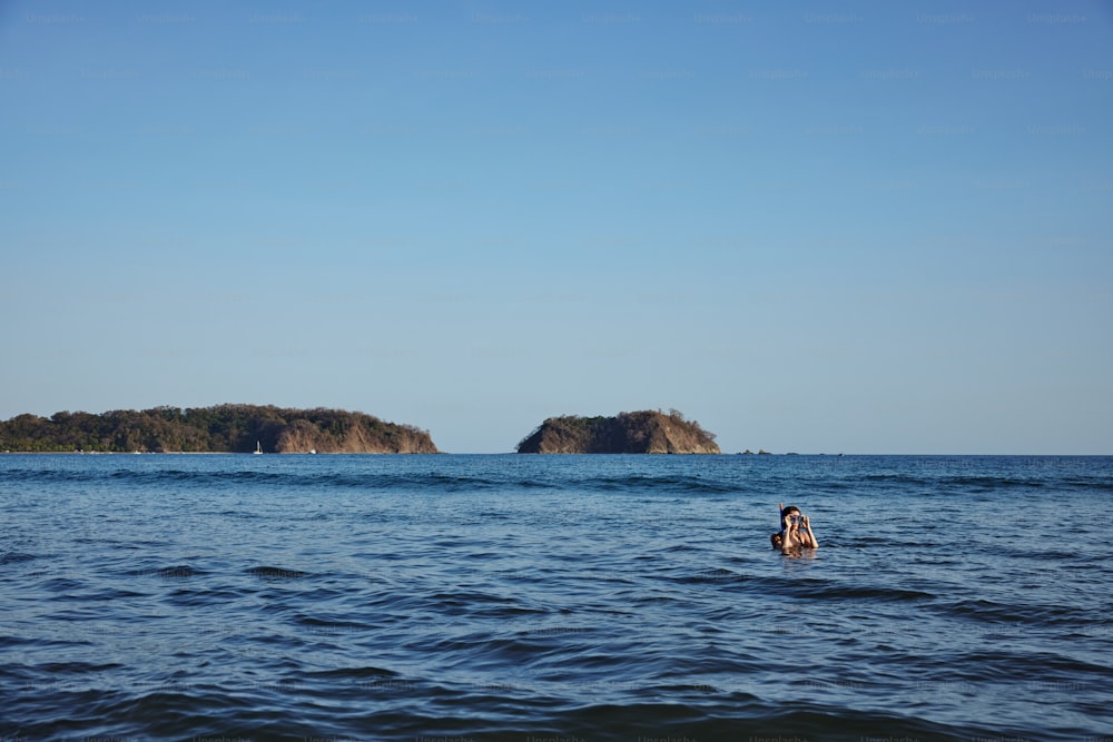 a person swimming in the ocean near a small island