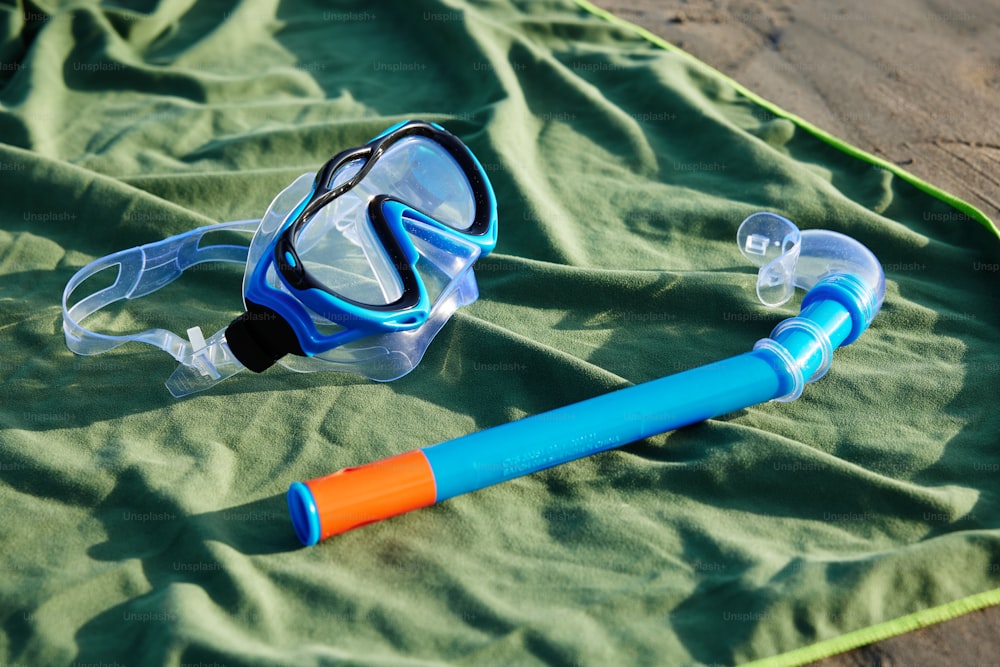 a pair of swimming goggles and a tube laying on a blanket