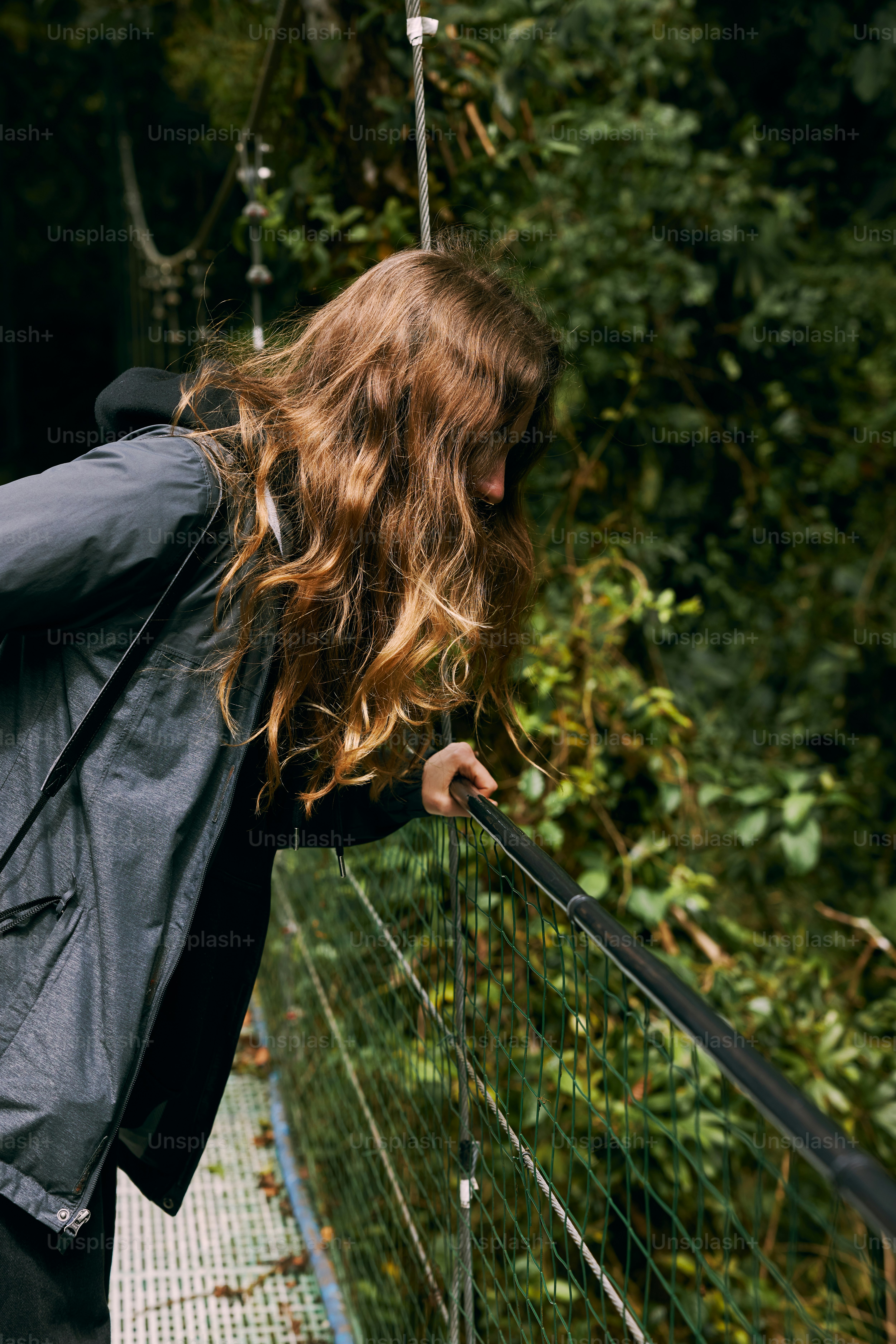 a woman with long hair walking across a bridge