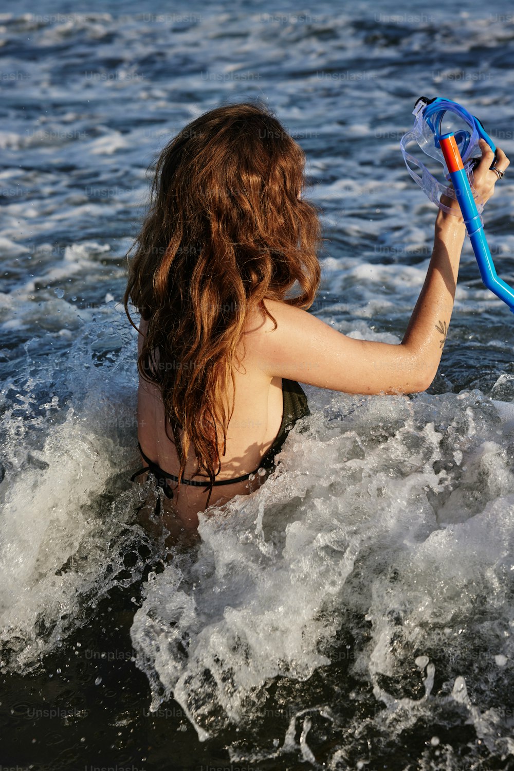 비키니를 입은 여자가 물에 파란 튜브를 들고 있다