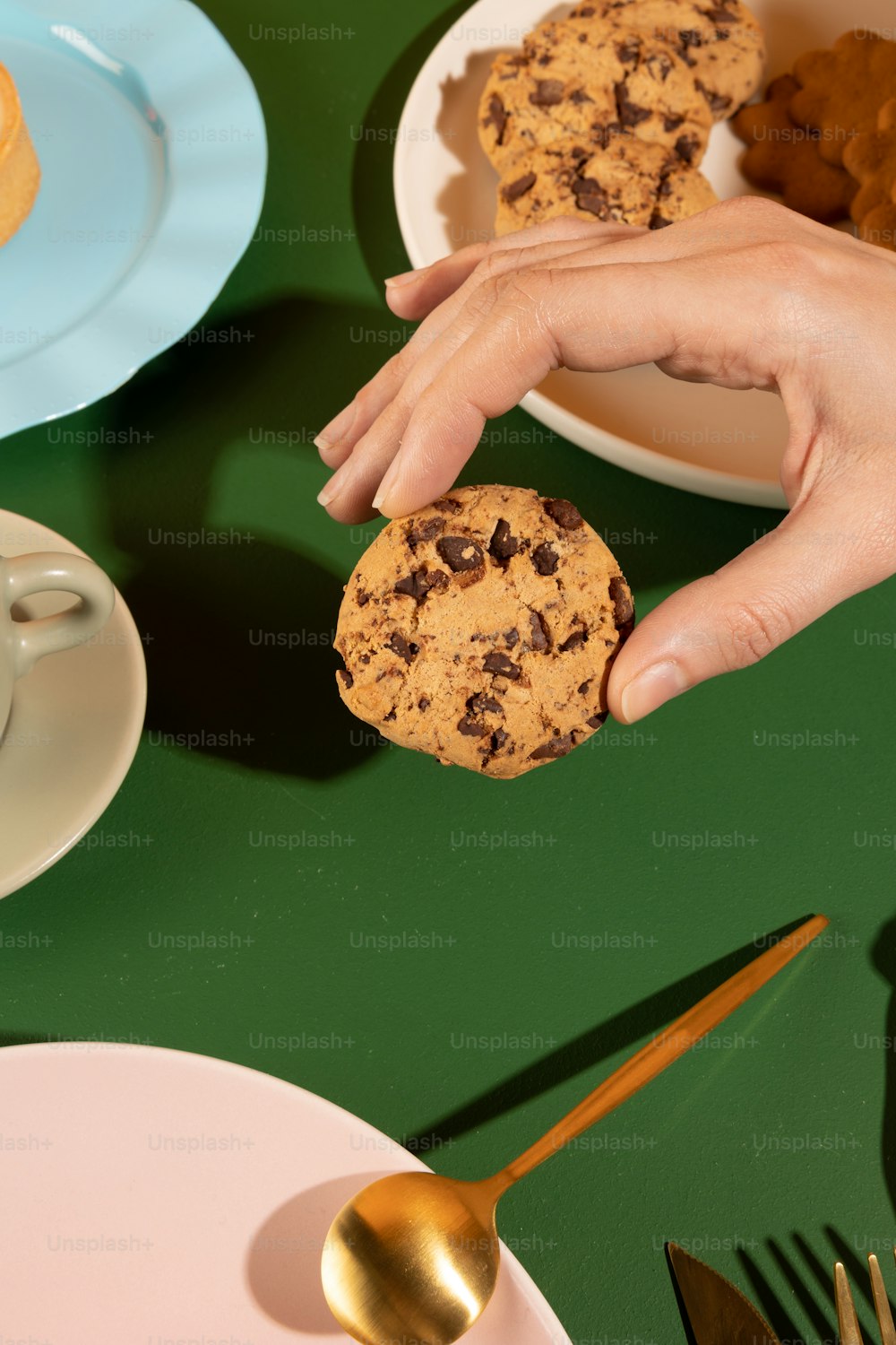 uma pessoa segurando um biscoito na frente de um prato de biscoitos