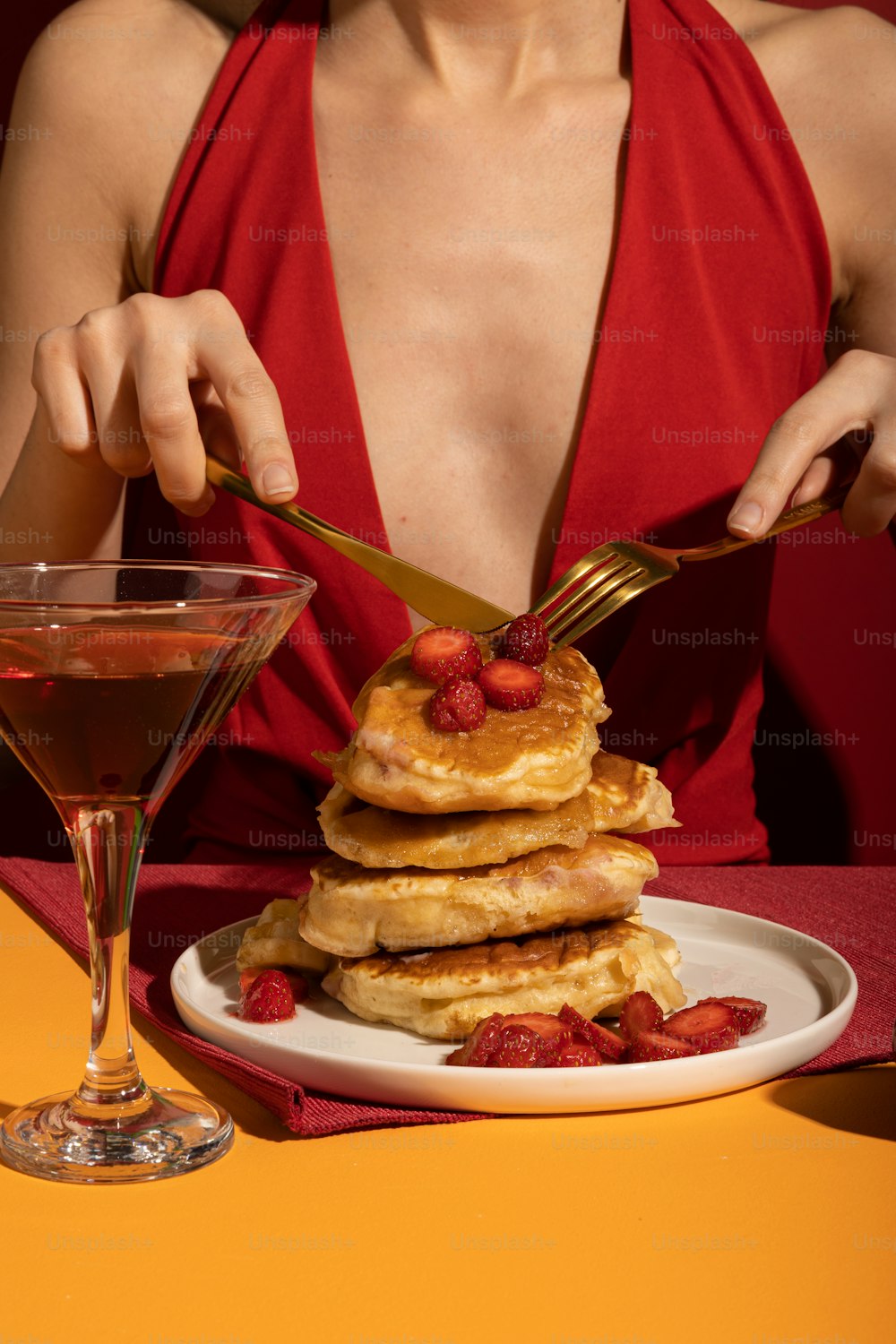 a woman sitting at a table with a plate of pancakes and a martini