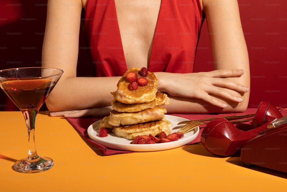 a woman in a red dress sitting at a table with a plate of pancakes and