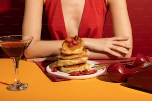 uma mulher em um vestido vermelho sentado em uma mesa com um prato de panquecas e