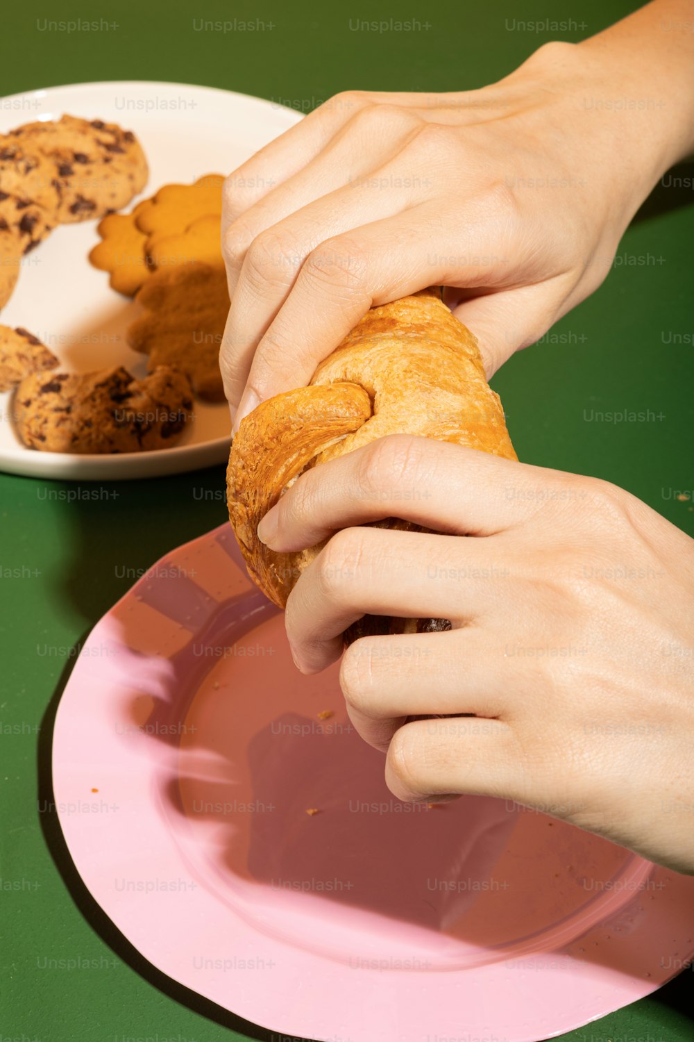 a person holding a doughnut in front of a plate of cookies
