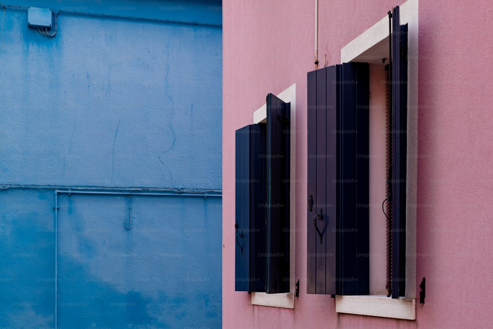 Un edificio rosa e blu con due finestre