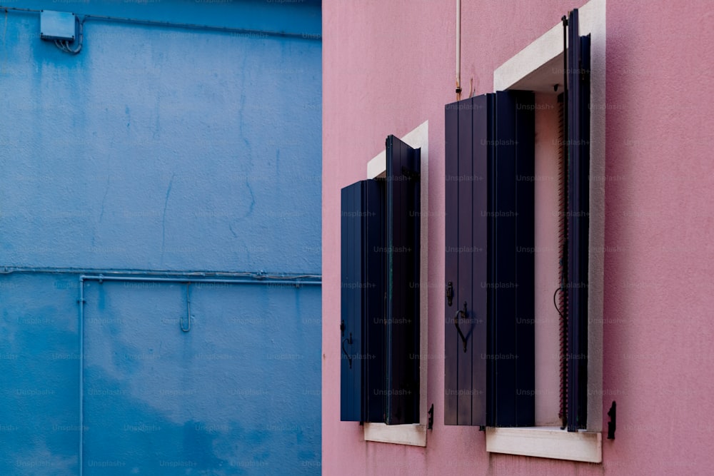 Un edificio rosa y azul con dos ventanas
