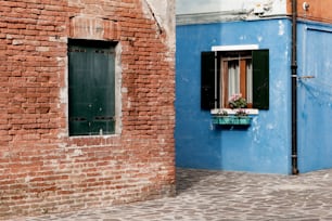 a blue building with a window and a brick wall