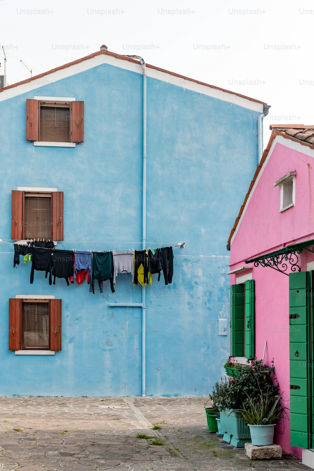 Kleidung, die zum Trocknen an einer Wäscheleine vor einem blauen Gebäude hängt