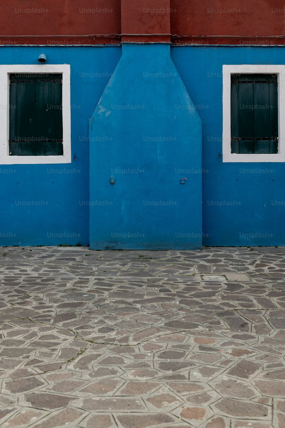Un idrante rosso seduto accanto a un edificio blu