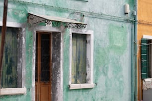 Ein grünes Gebäude mit zwei Fenstern und einer Tür