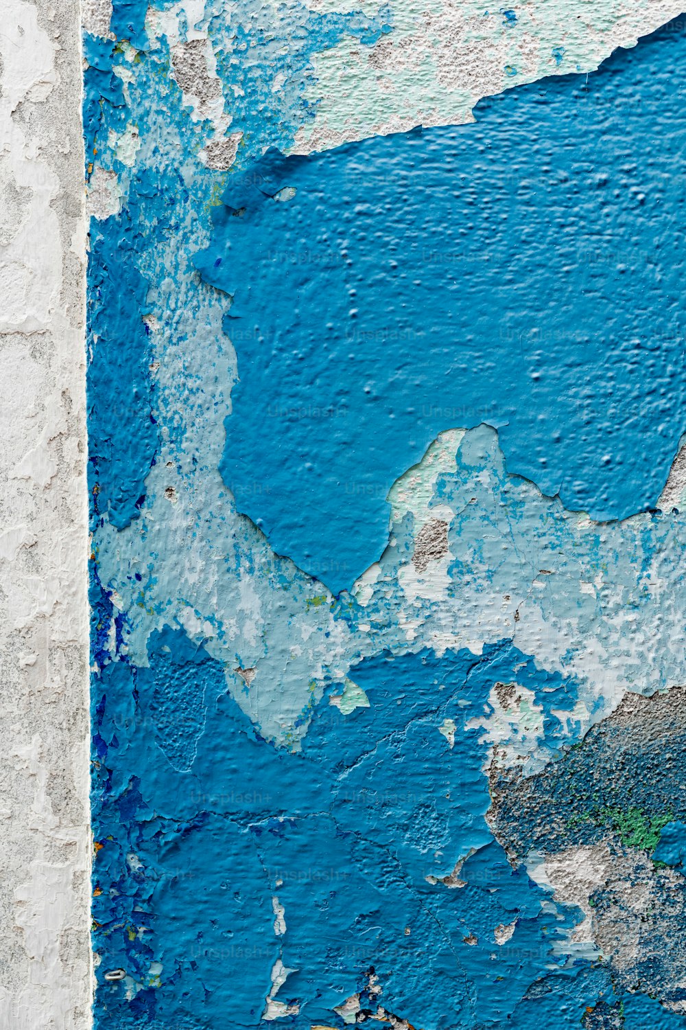 a blue and white wall with peeling paint