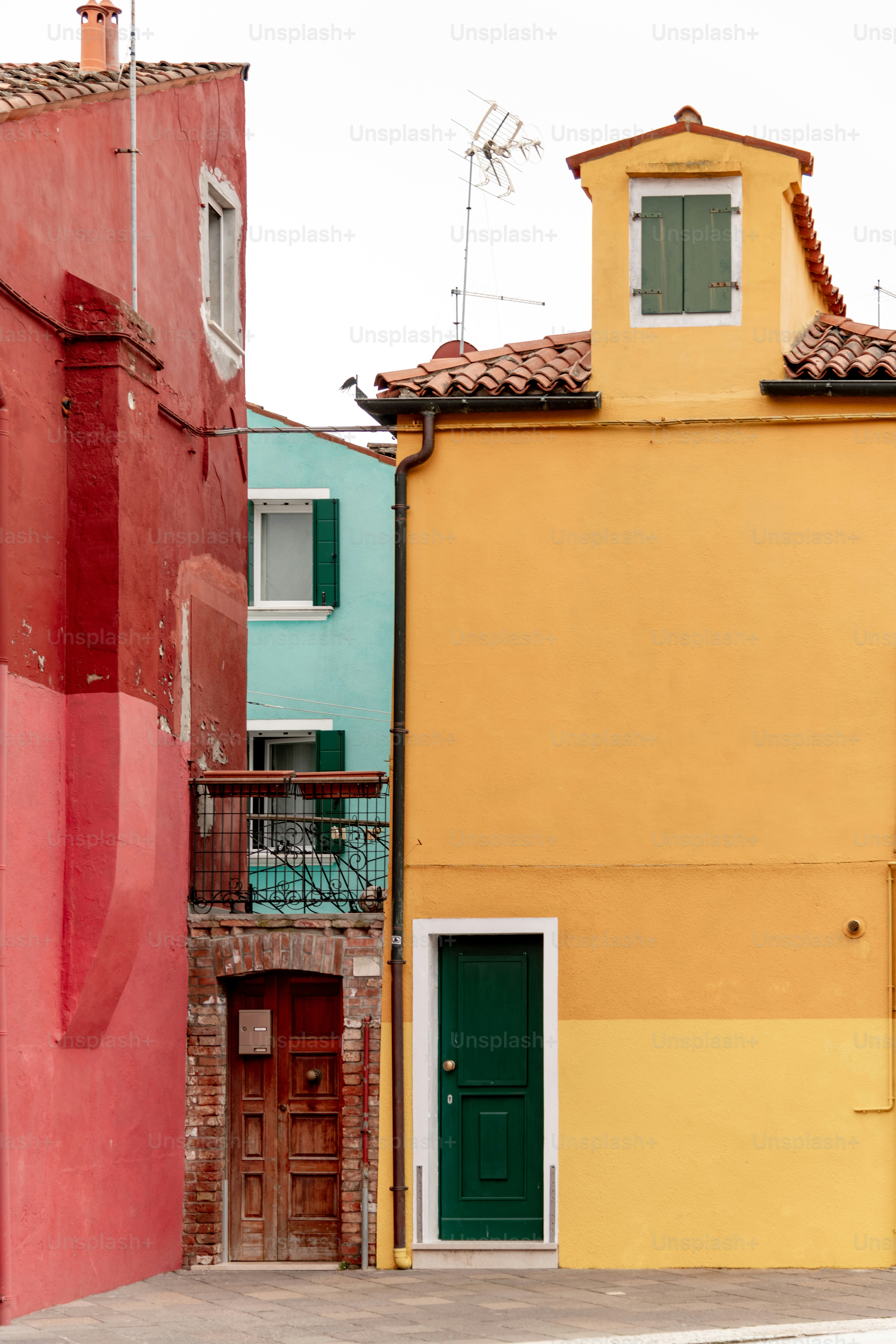 a yellow building with a green door next to a red building