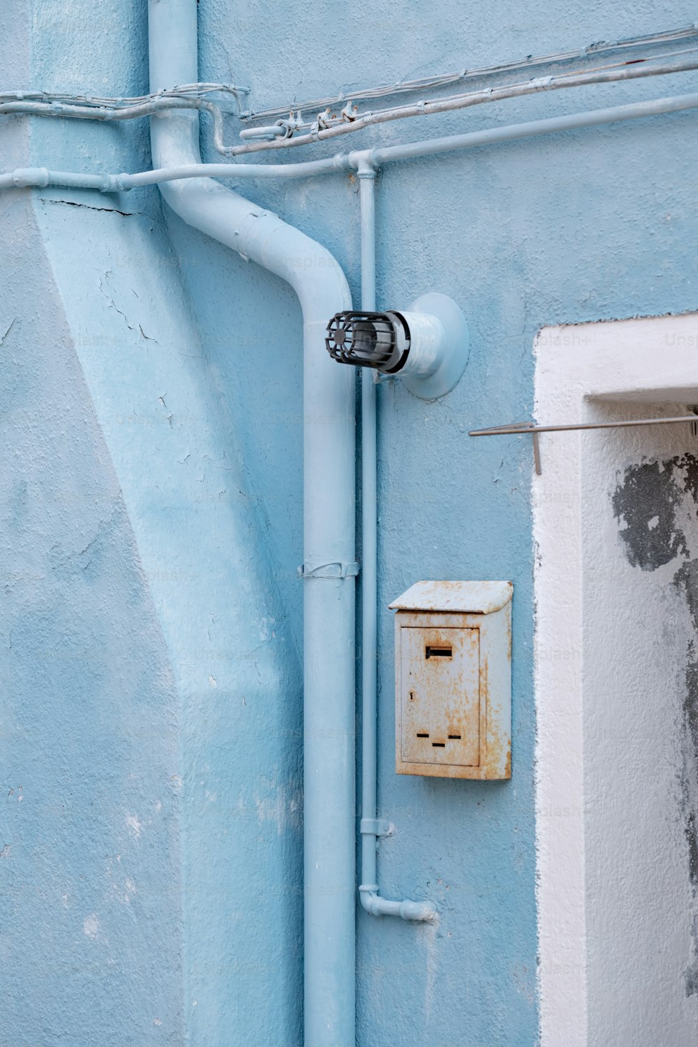 un interrupteur sur un mur bleu à côté d’une fenêtre