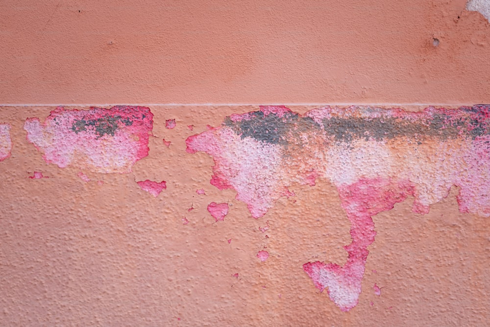 una pared roja y rosa con pintura descascarada
