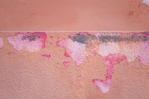 a red and pink wall with peeling paint on it