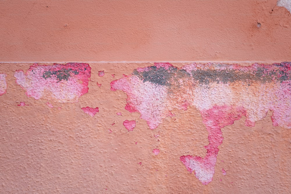 a red and pink wall with peeling paint on it