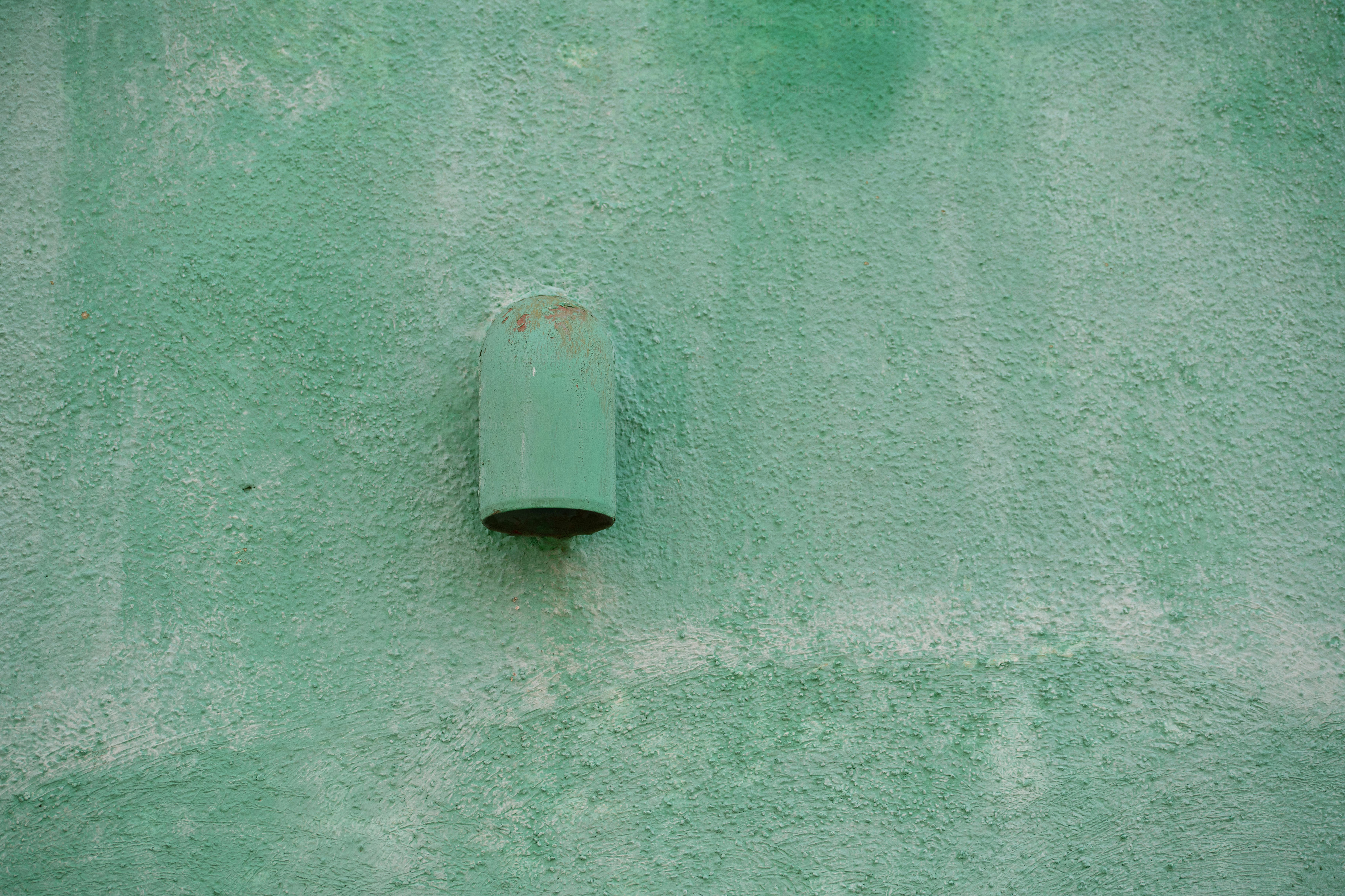 a green wall with a pipe sticking out of it