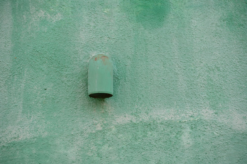 un muro verde con un tubo che sporge da esso