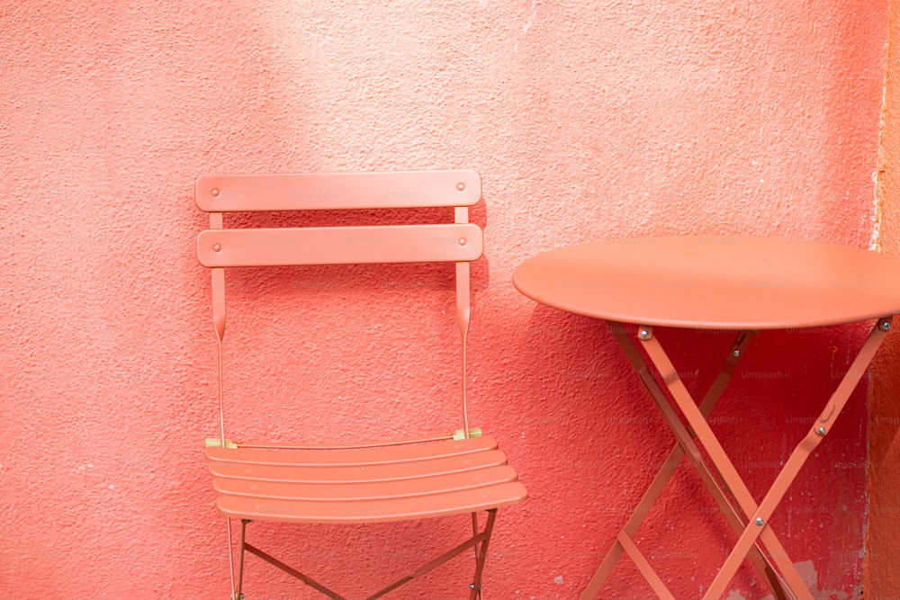 ein Stuhl und ein Tisch an einer rosa Wand
