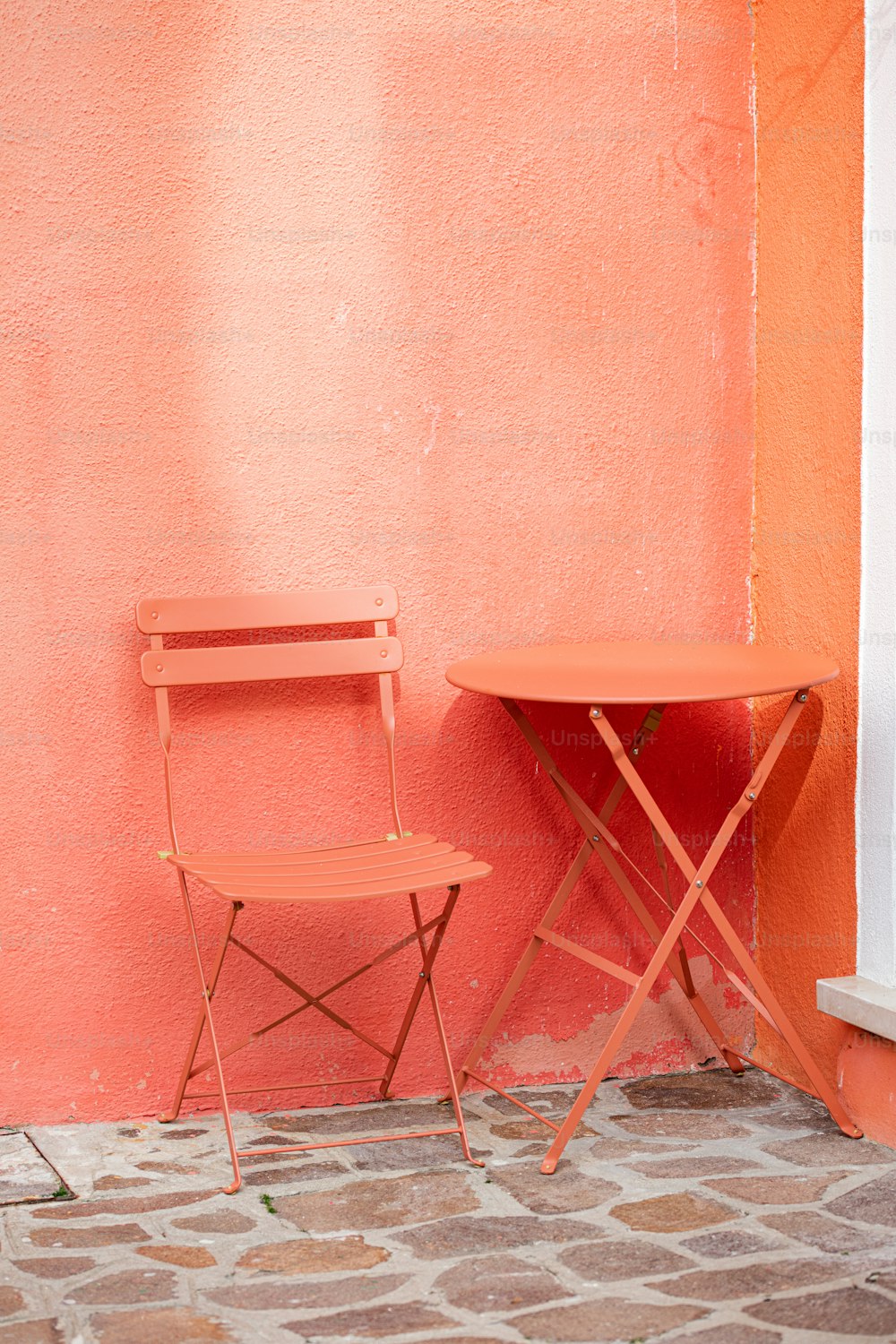 uma cadeira e uma mesa contra uma parede rosa
