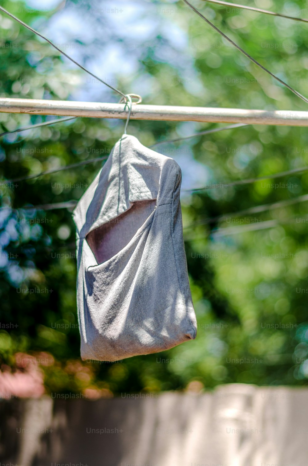 a bag hanging from a clothes line with trees in the background