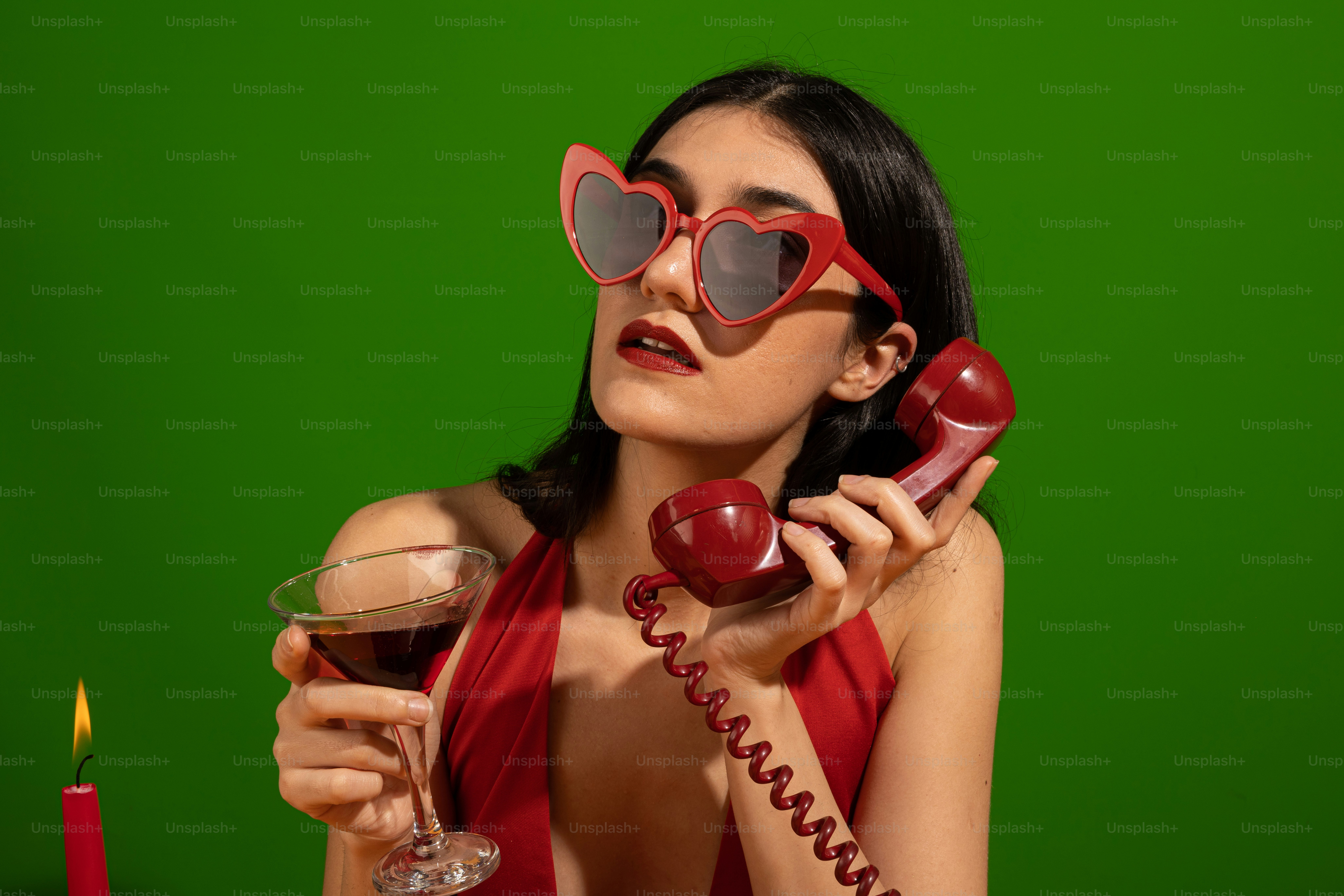 A woman in a red dress holding a glass of wine and a phone photo ...