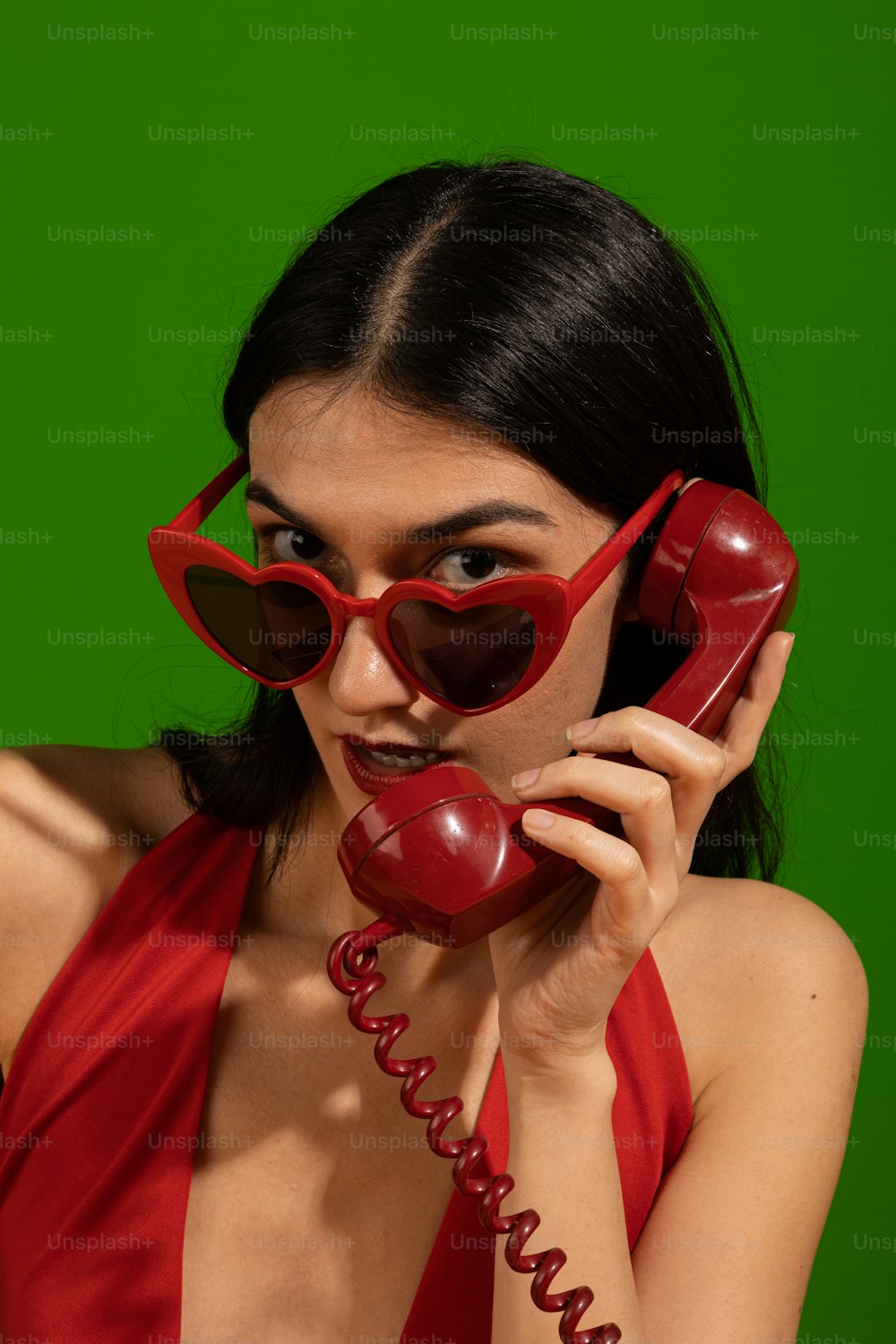 Una donna in un vestito rosso che parla su un telefono rosso