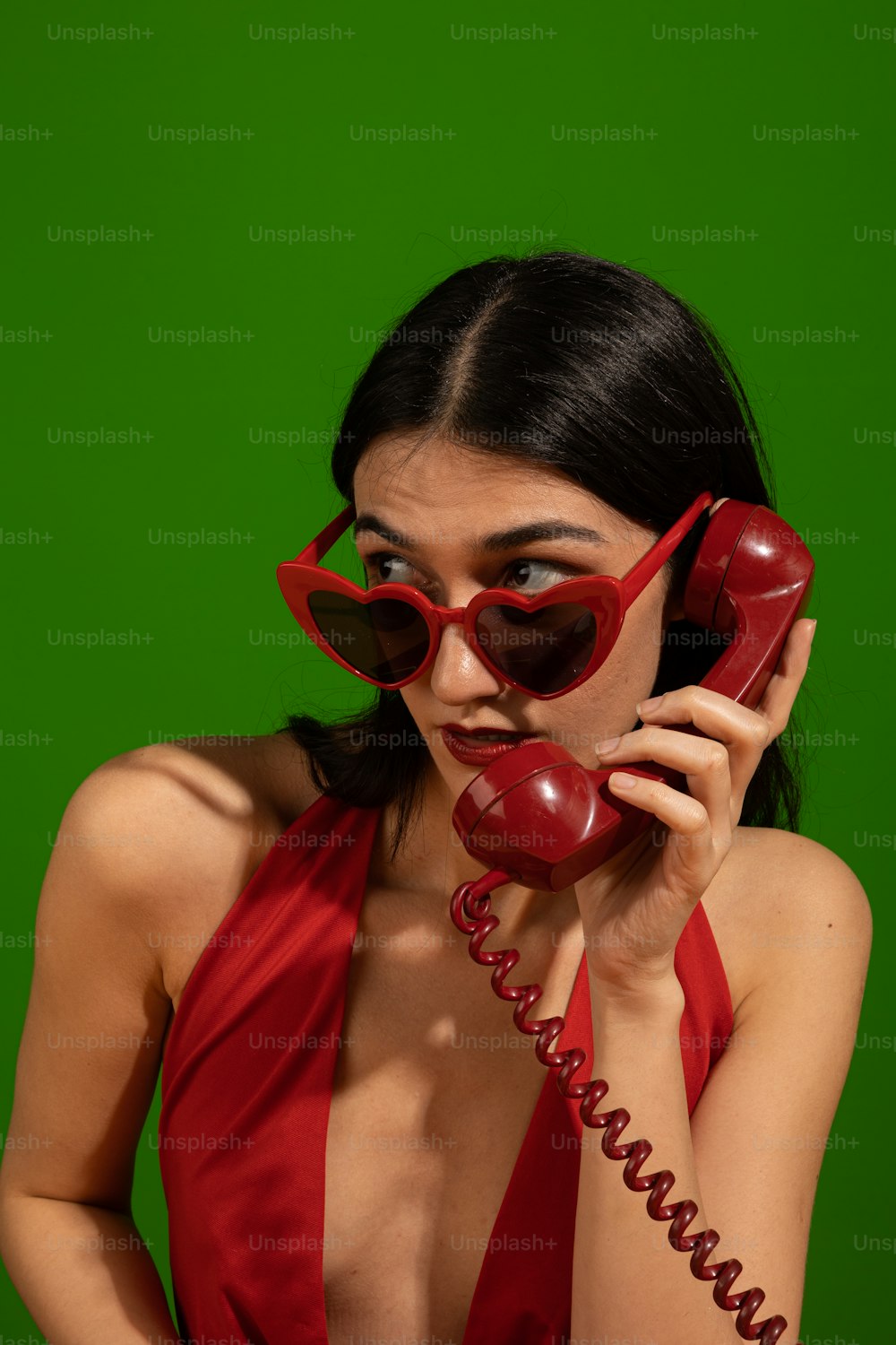 Una mujer con un vestido rojo hablando por un teléfono rojo