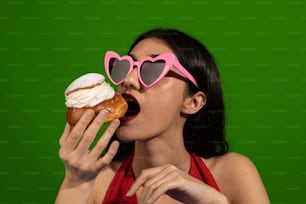 a woman eating a doughnut wearing heart shaped sunglasses