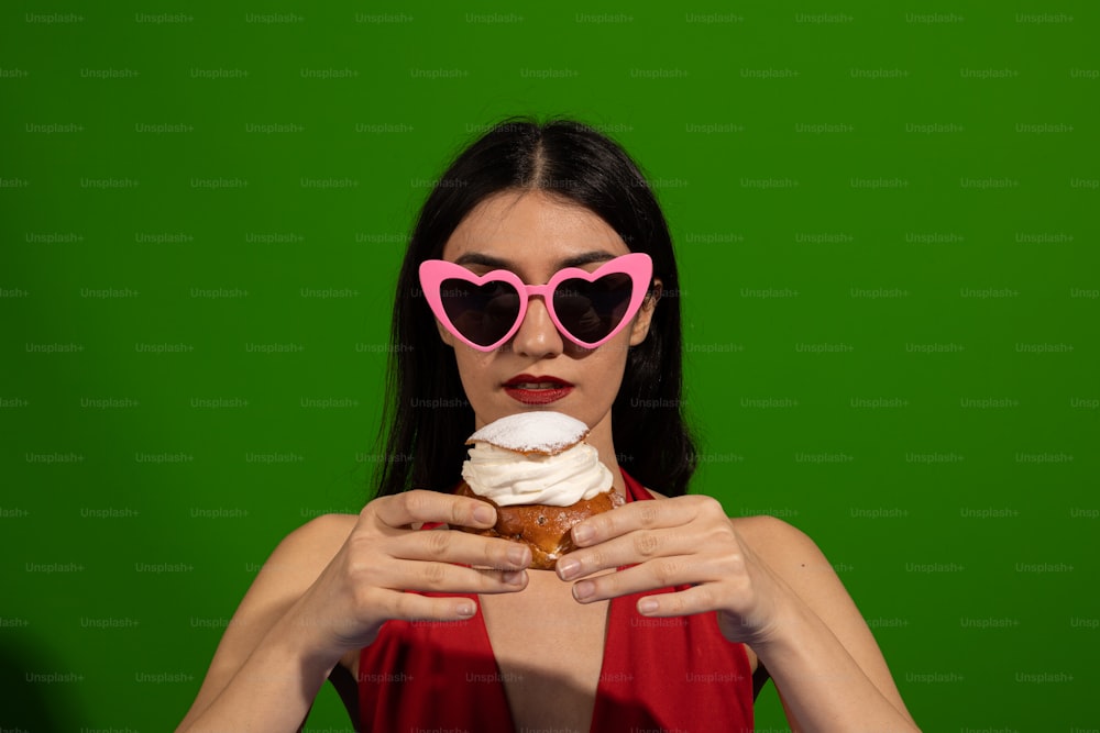 a woman wearing heart shaped sunglasses holding a doughnut