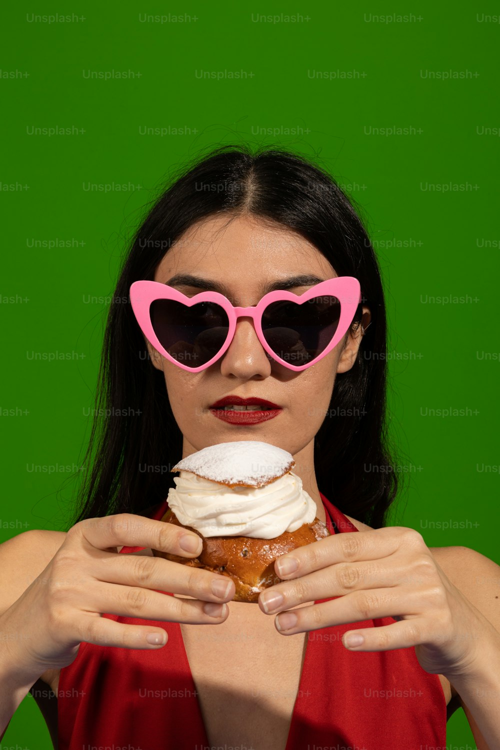 a woman wearing pink heart shaped sunglasses holding a doughnut