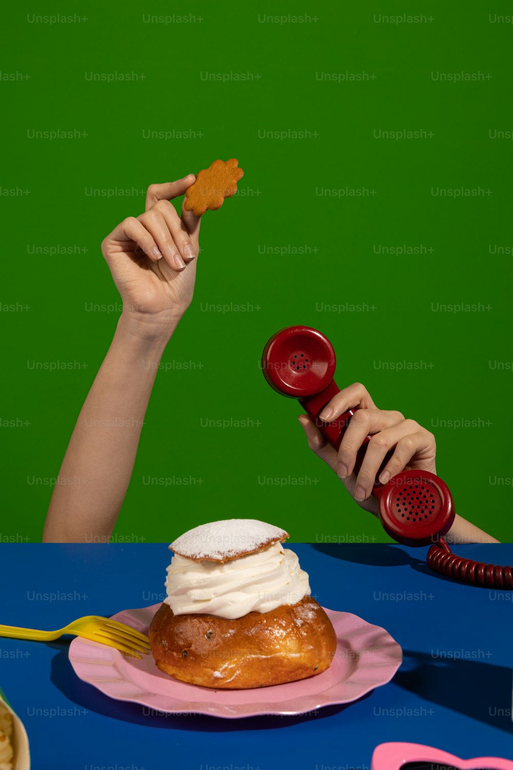 a woman holding a red phone next to a pastry on a pink plate