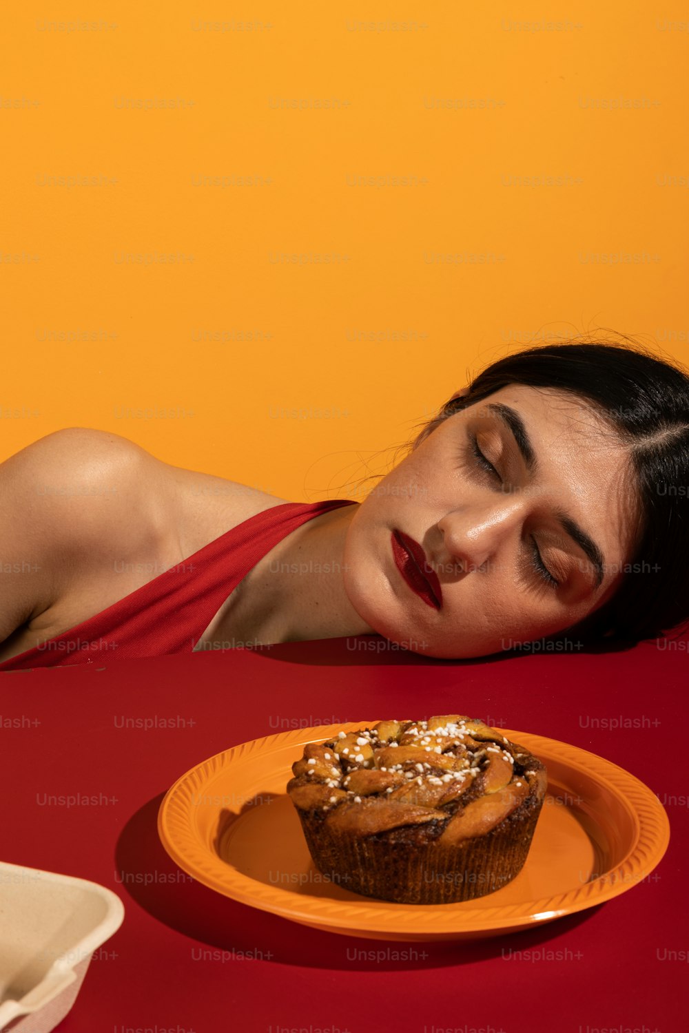 a woman laying down next to a plate with a cupcake on it