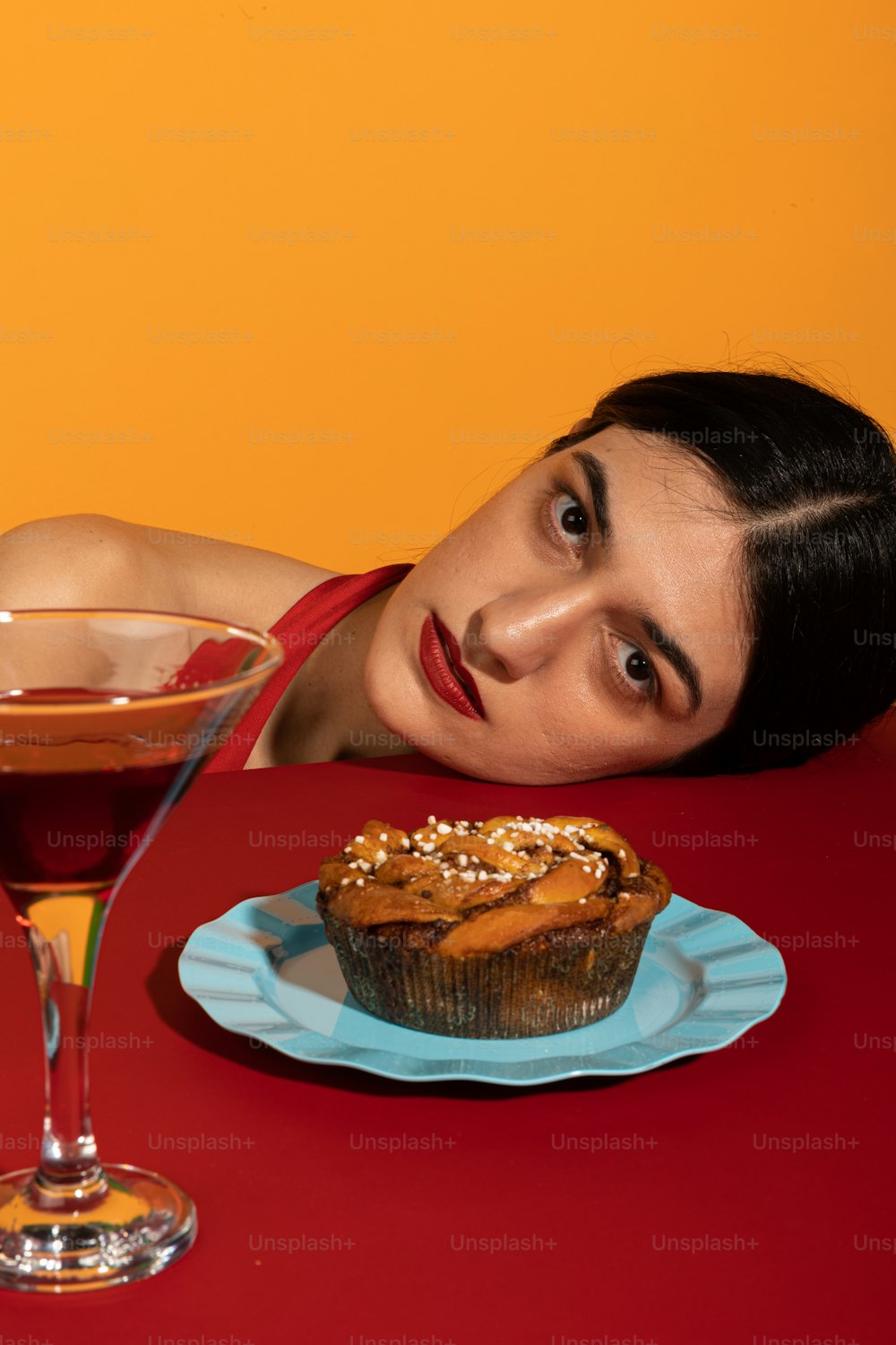 Una mujer sentada en una mesa con una magdalena y una bebida