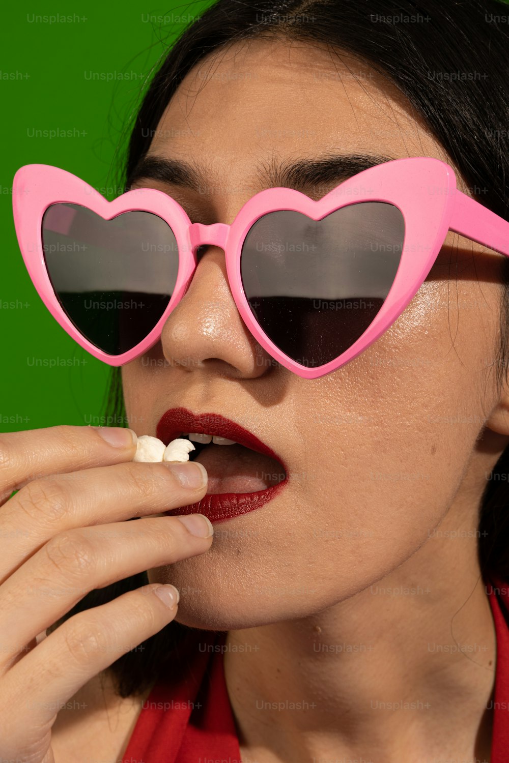 a woman wearing heart shaped sunglasses eating a piece of food
