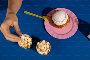 a pink plate topped with popcorn next to a cup of ice cream