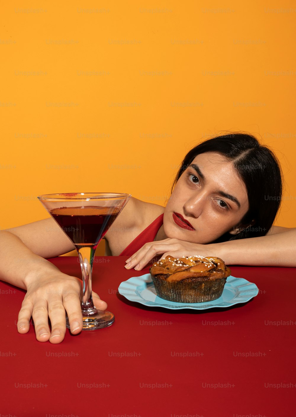 Una mujer sentada en una mesa con una magdalena y una bebida