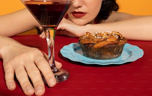 a woman sitting at a table with a glass of wine and a muffin