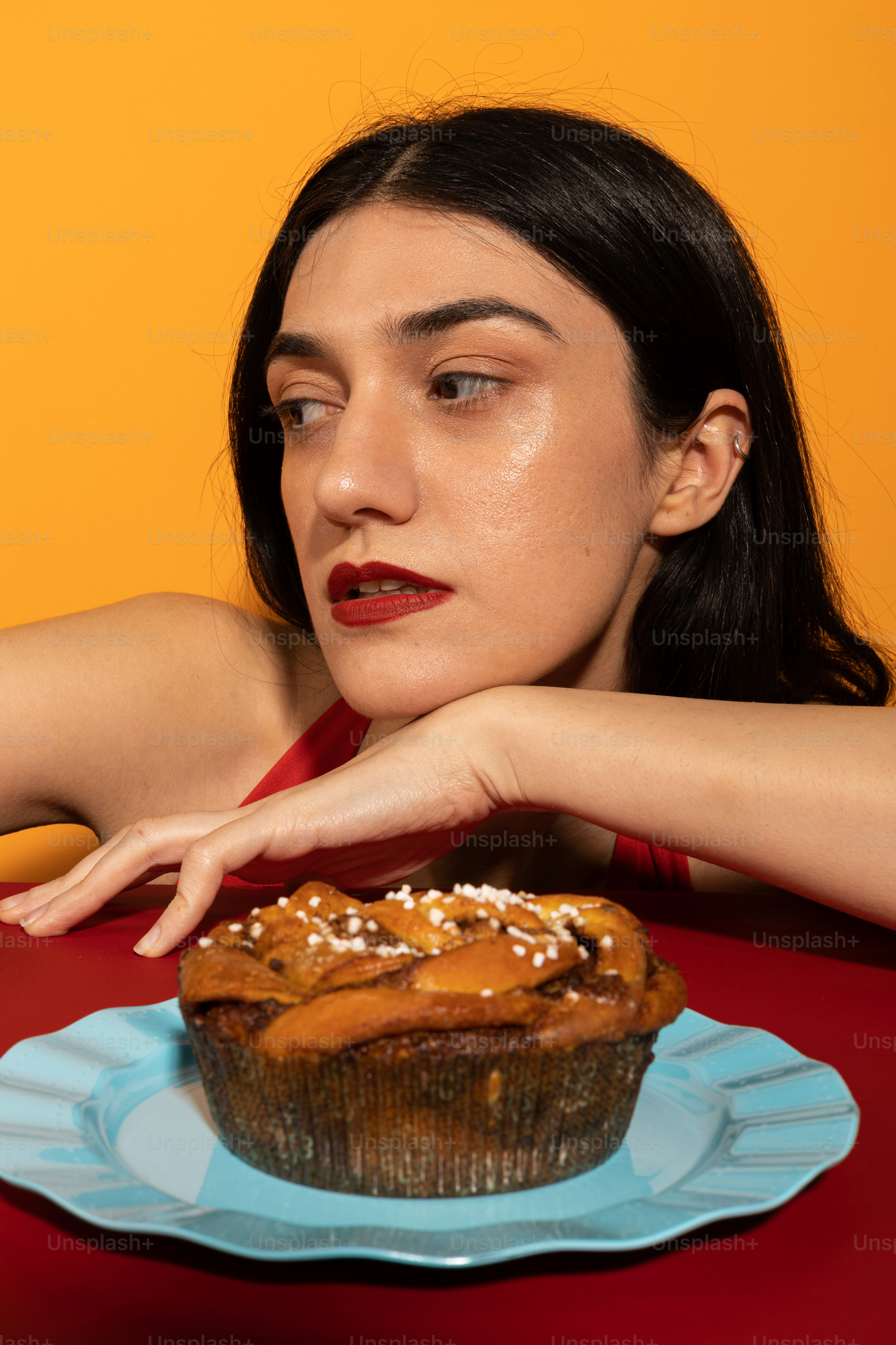 Una mujer sentada en una mesa con una magdalena frente a ella