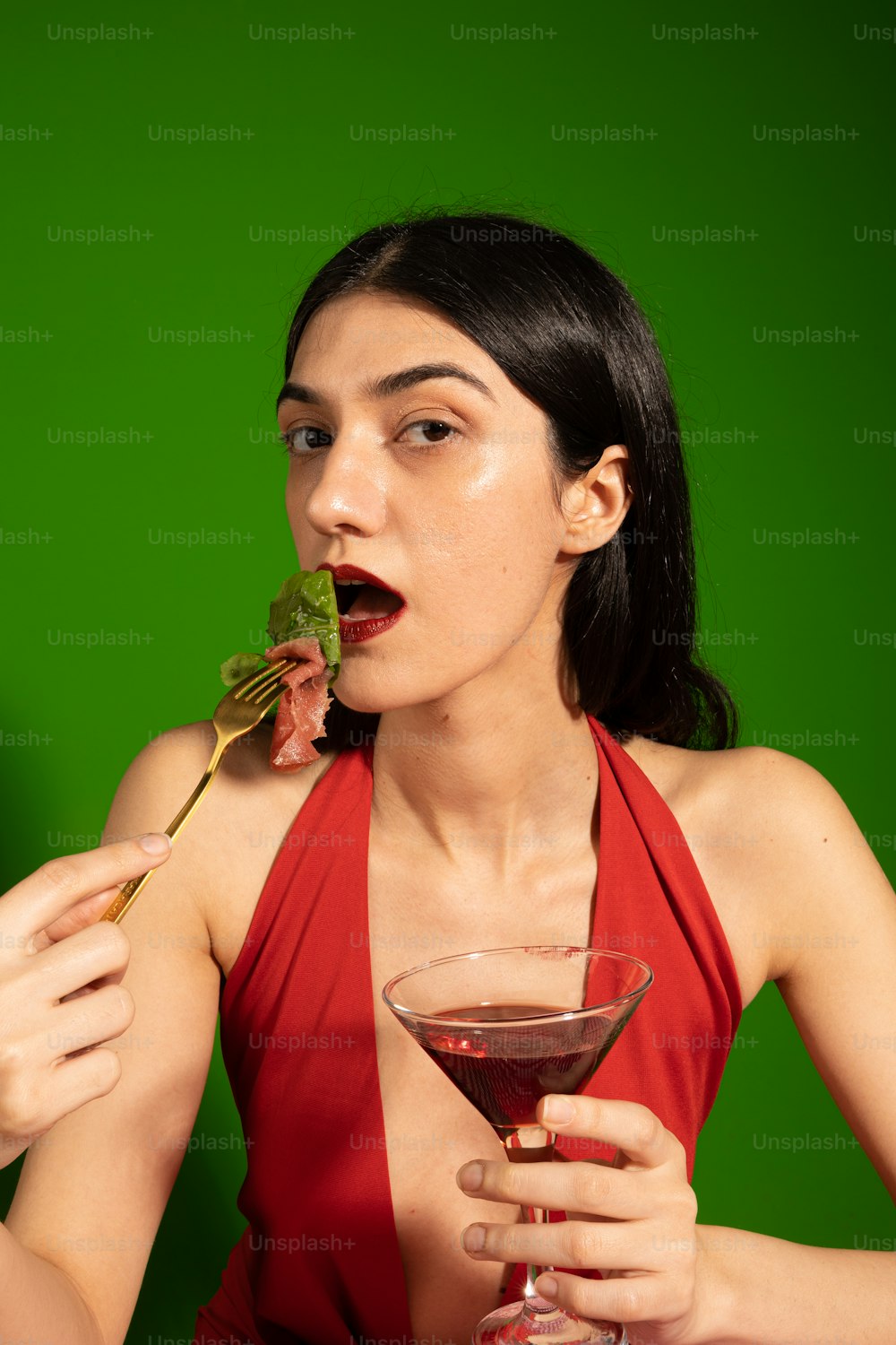 a woman in a red dress eating a piece of food