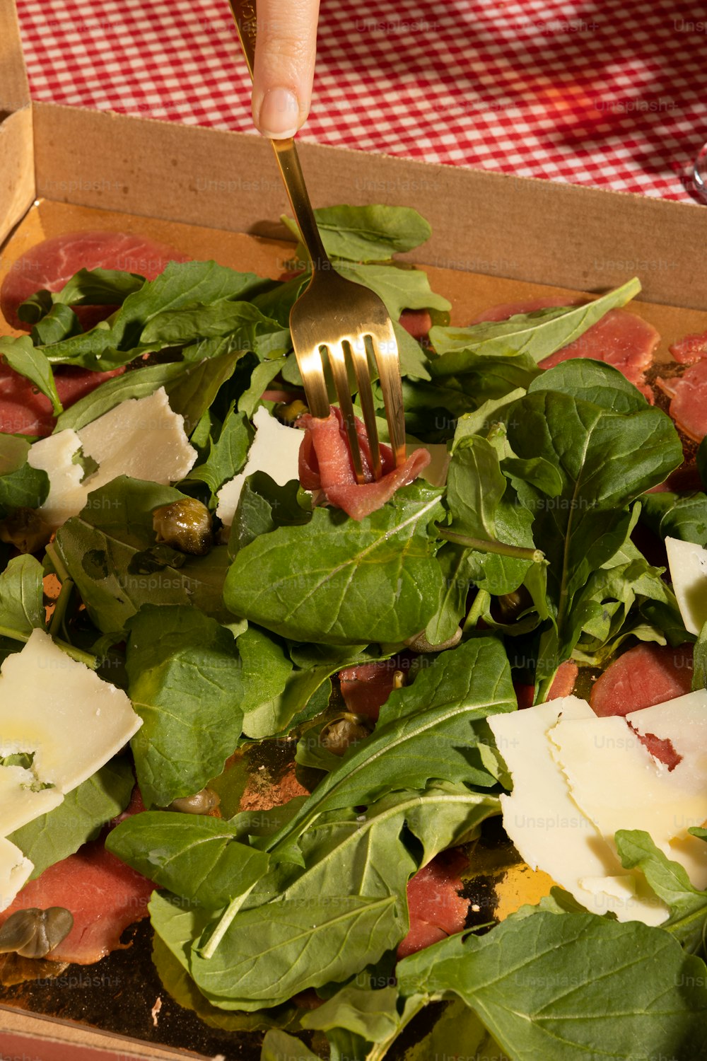 a person holding a fork over a green salad
