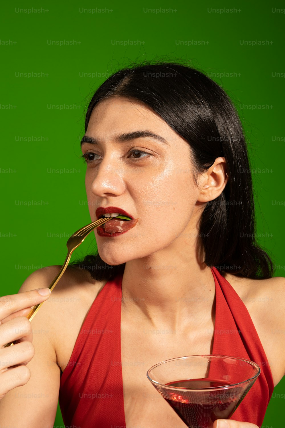 a woman in a red dress holding a spoon in her mouth