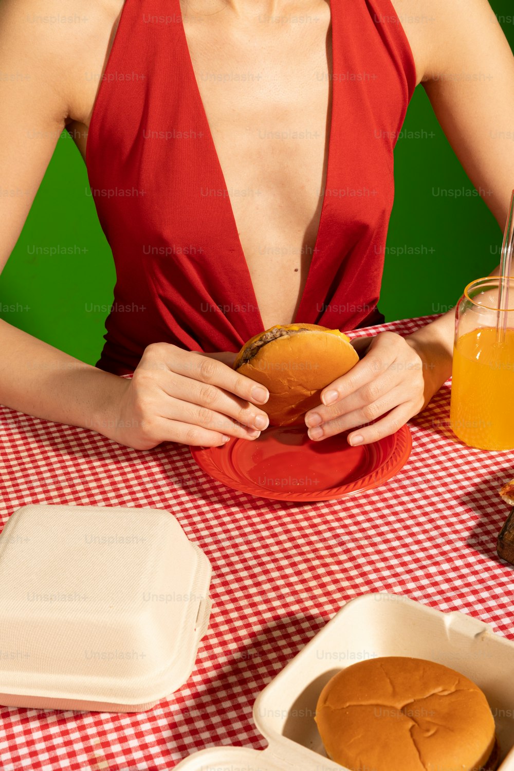 a woman sitting at a table with a hamburger in front of her