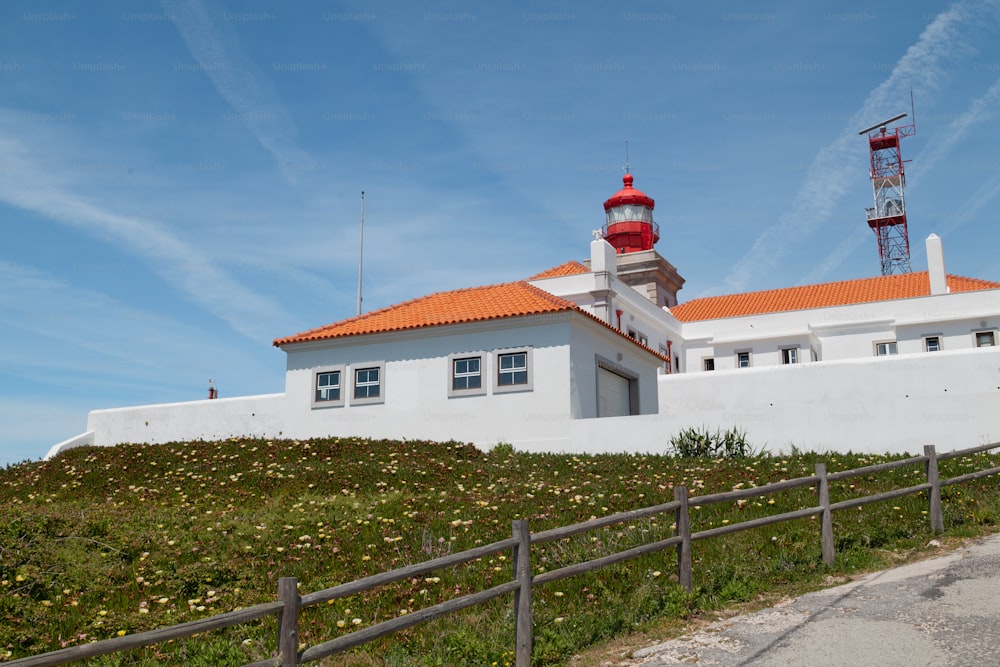 a white building with a red roof on a hill