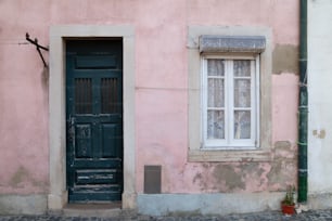 a pink building with a black door and window